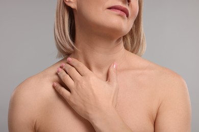 Photo of Woman touching her neck on grey background, closeup