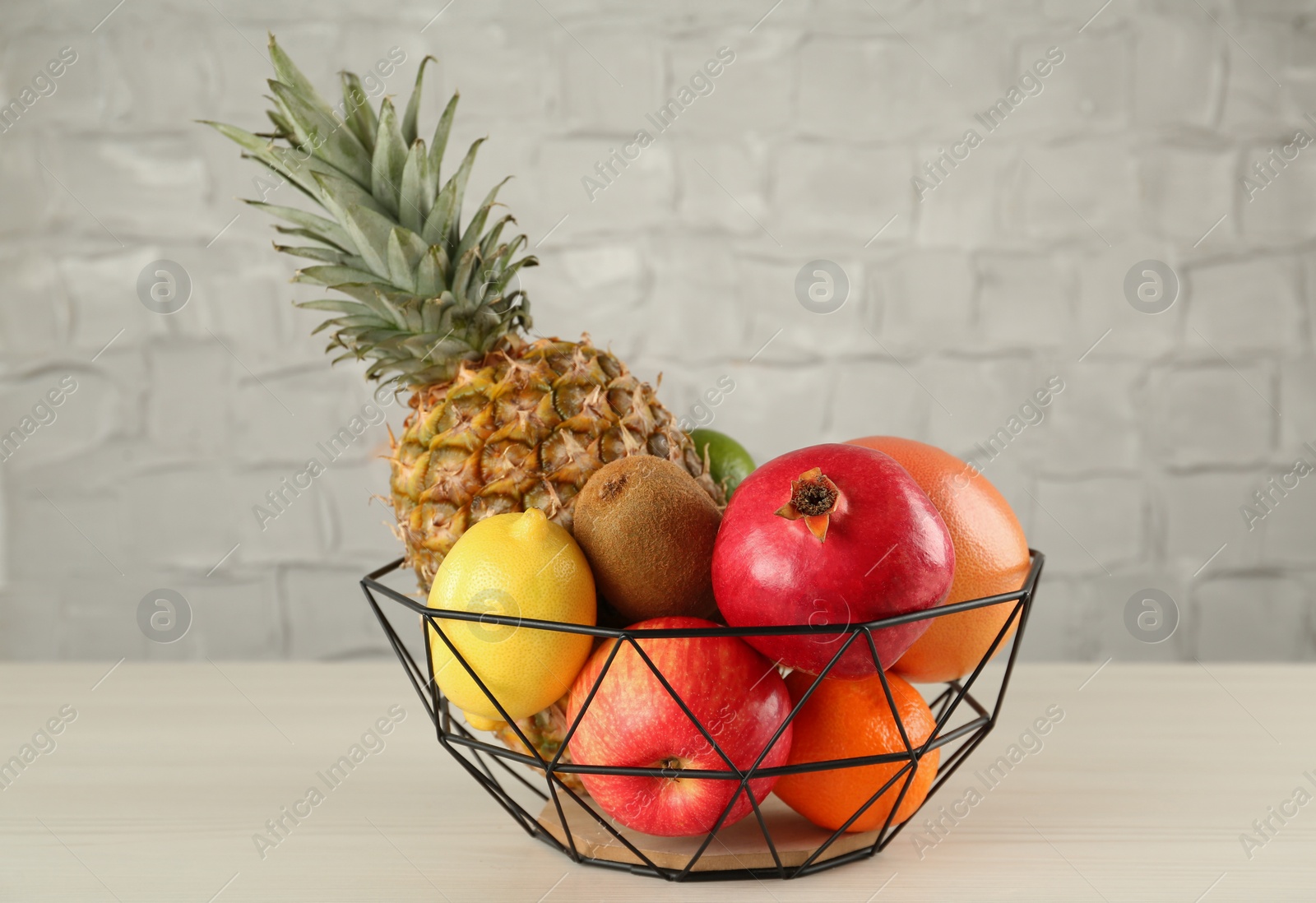 Photo of Fresh ripe fruits in metal bowl on wooden table