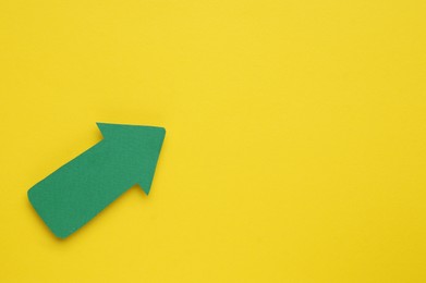 Photo of Paper arrow on yellow background, top view. Space for text
