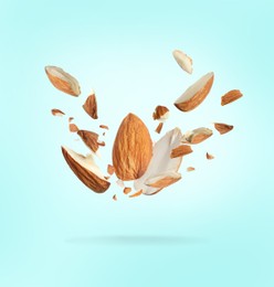 Image of Pieces of tasty almonds falling on light blue background
