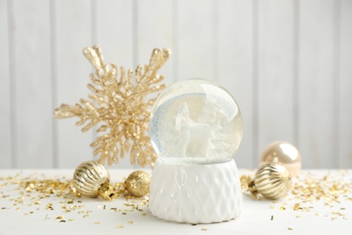 Beautiful snow globe and Christmas balls on white table