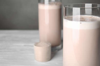 Photo of Glass with protein shake on white table, closeup. Space for text