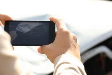 Man photographing broken car after accident for insurance claim, closeup