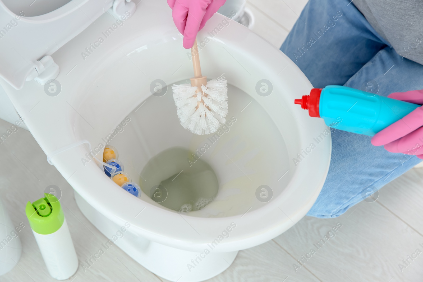 Photo of Woman cleaning toilet bowl in bathroom