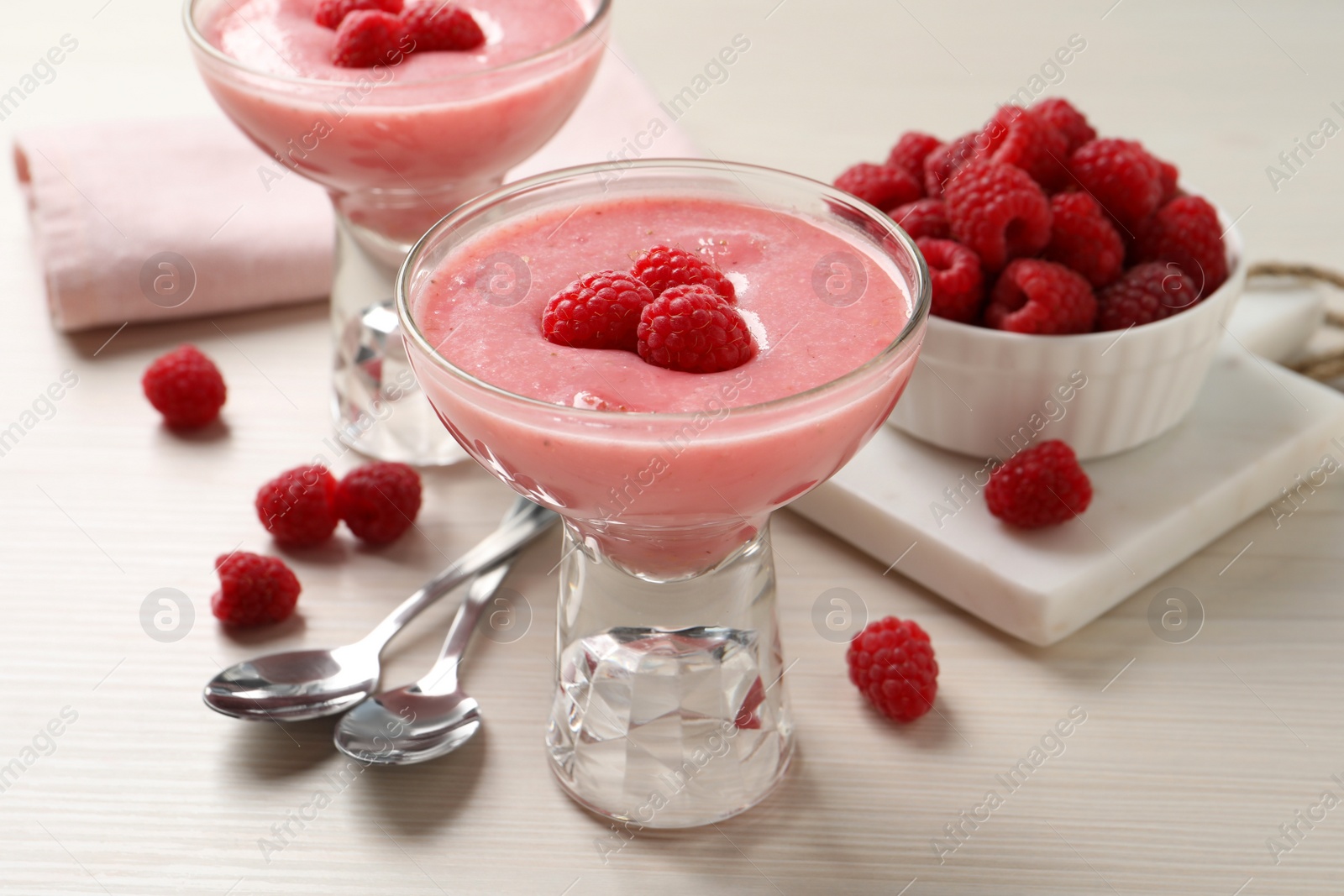 Photo of Delicious raspberry mousse on white wooden table