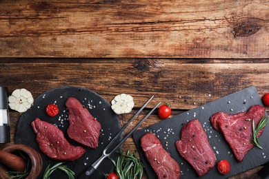 Photo of Fresh raw meat steaks and spices on wooden table, flat lay. Space for text