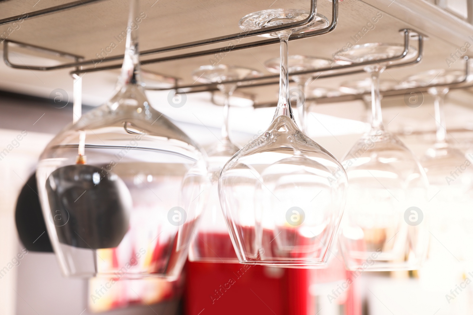 Photo of Set of empty clean glasses on bar racks, closeup