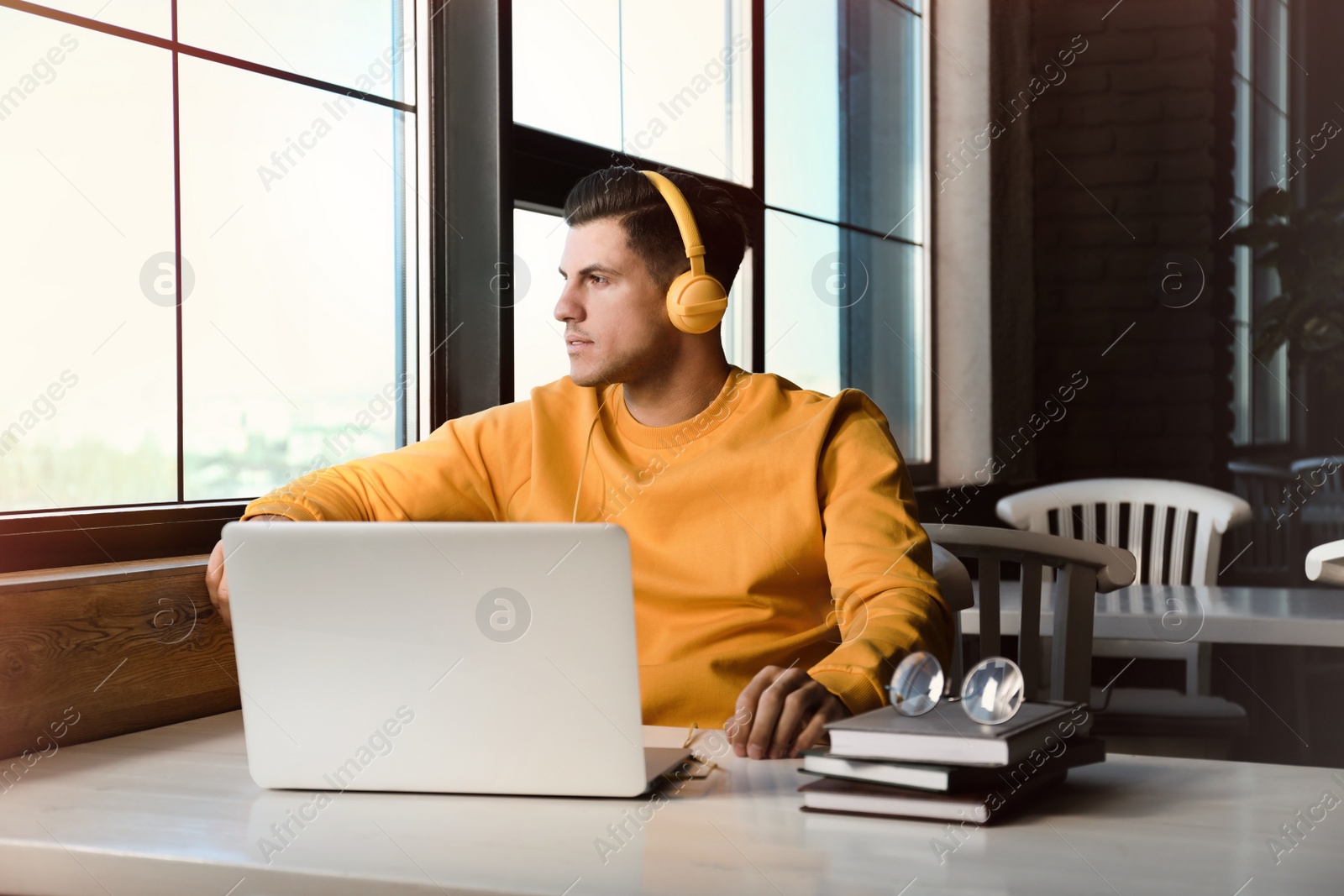 Photo of Man listening to audiobook at table in cafe