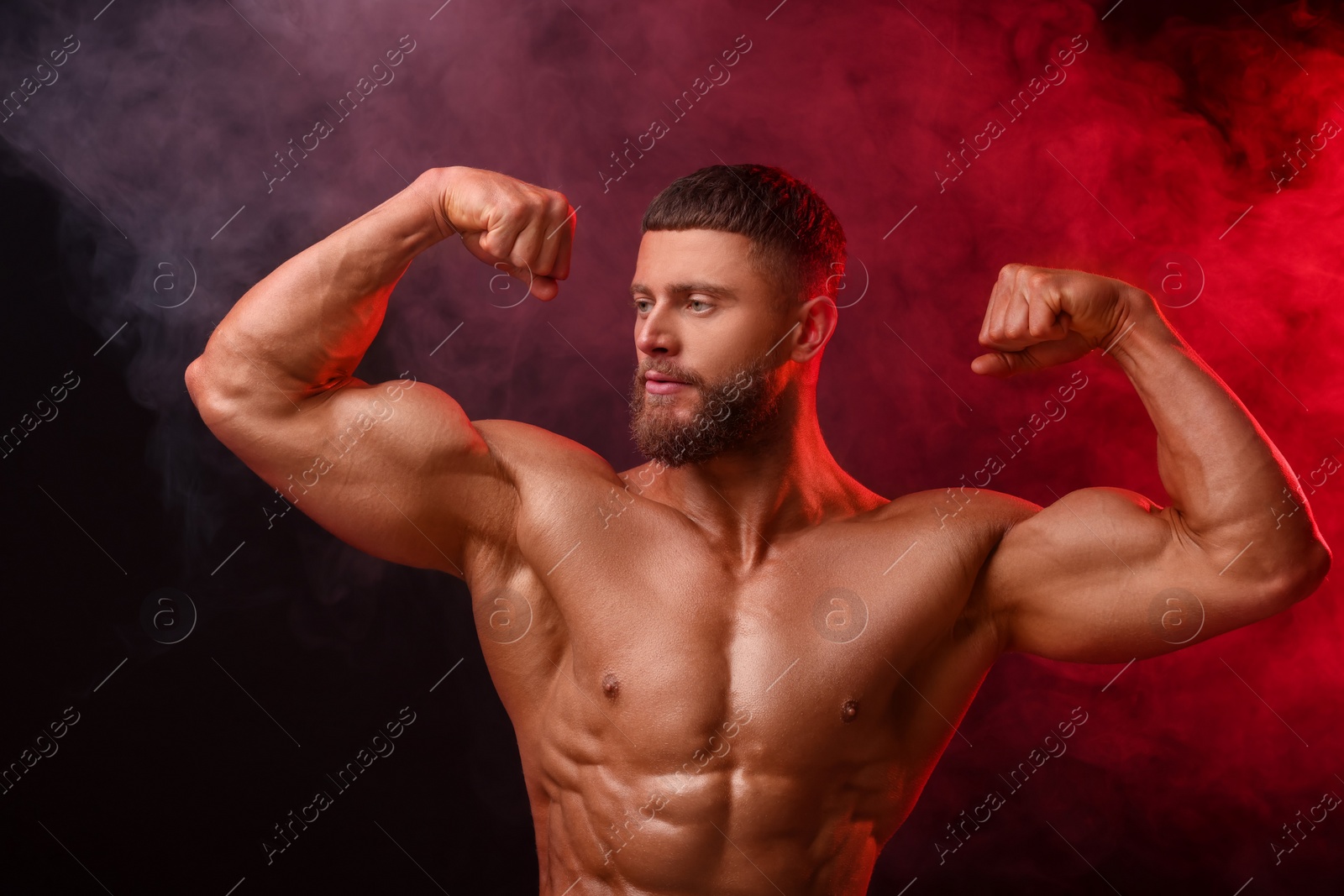 Photo of Young bodybuilder with muscular body in smoke on color background