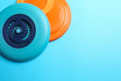 Photo of Plastic frisbee disks and ring on light blue background, flat lay. Space for text