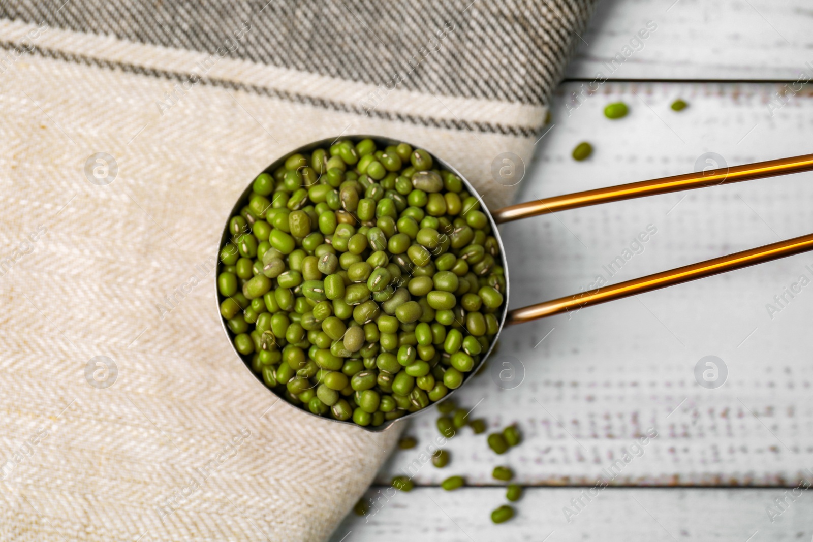 Photo of Scoop with mung beans on white wooden table, flat lay