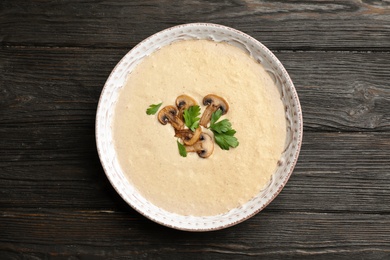 Bowl of fresh homemade mushroom soup on wooden background, top view