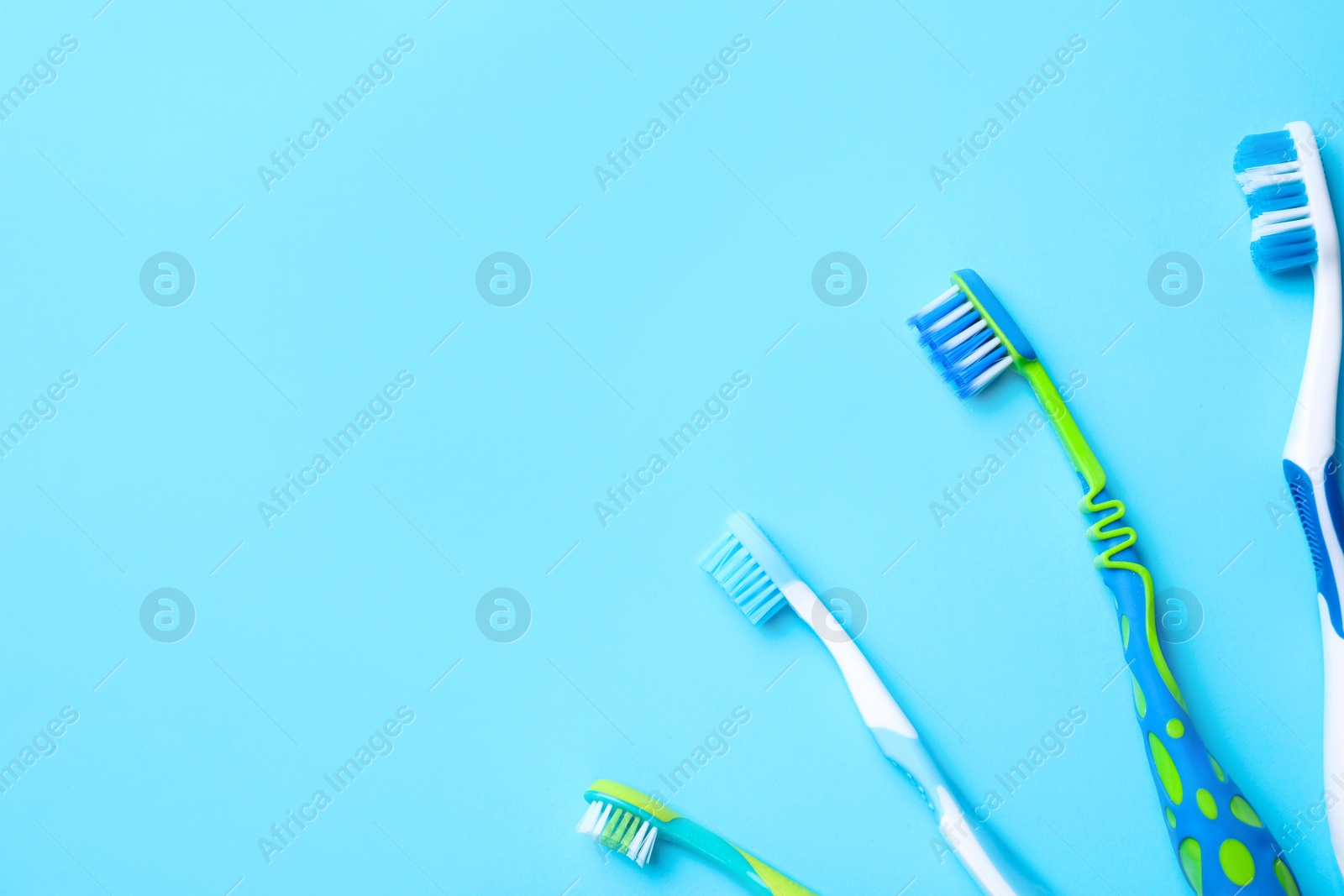Photo of Different toothbrushes and space for text on light blue background, flat lay
