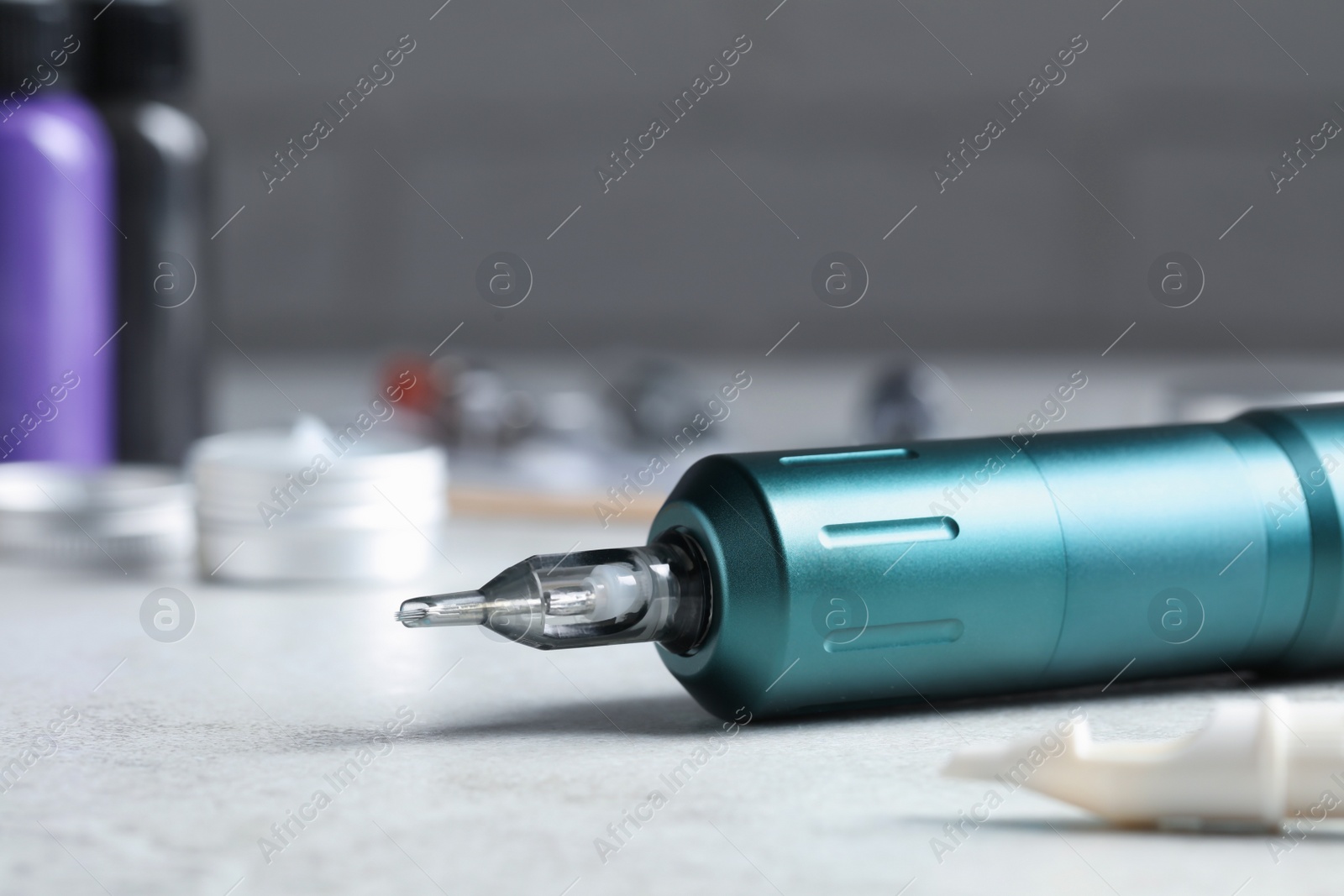 Photo of Modern professional tattoo machine on white table, closeup