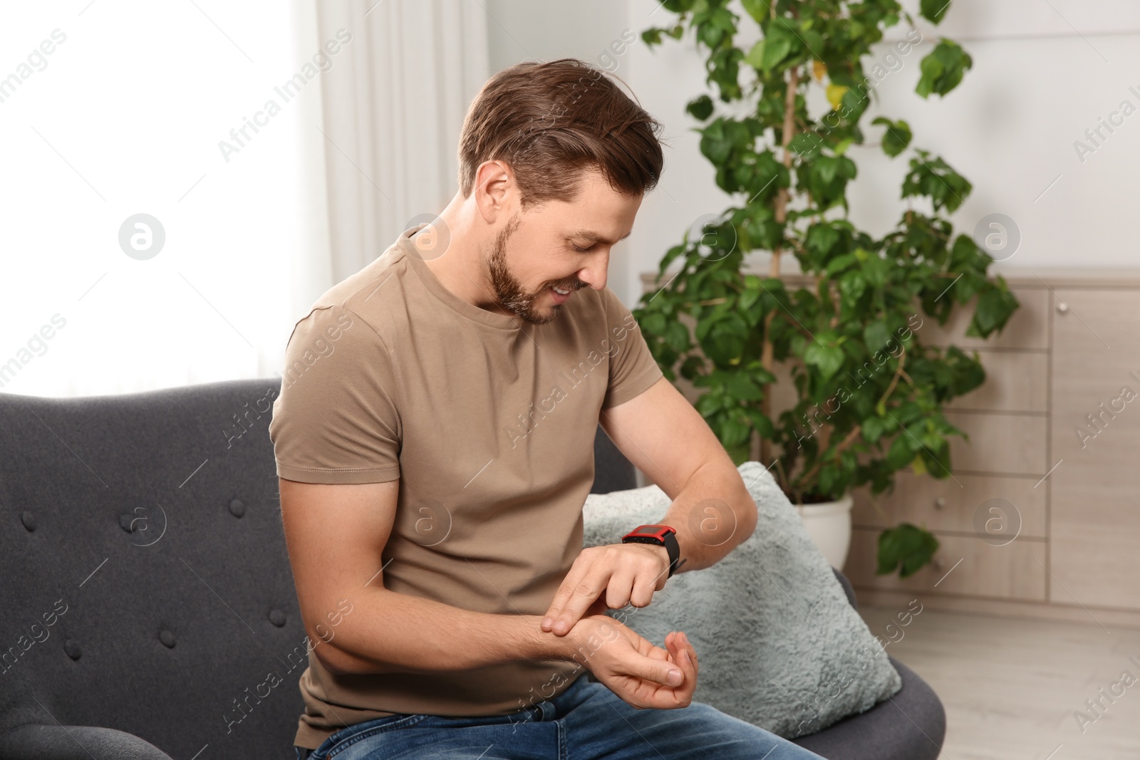 Photo of Man checking pulse with fingers at home