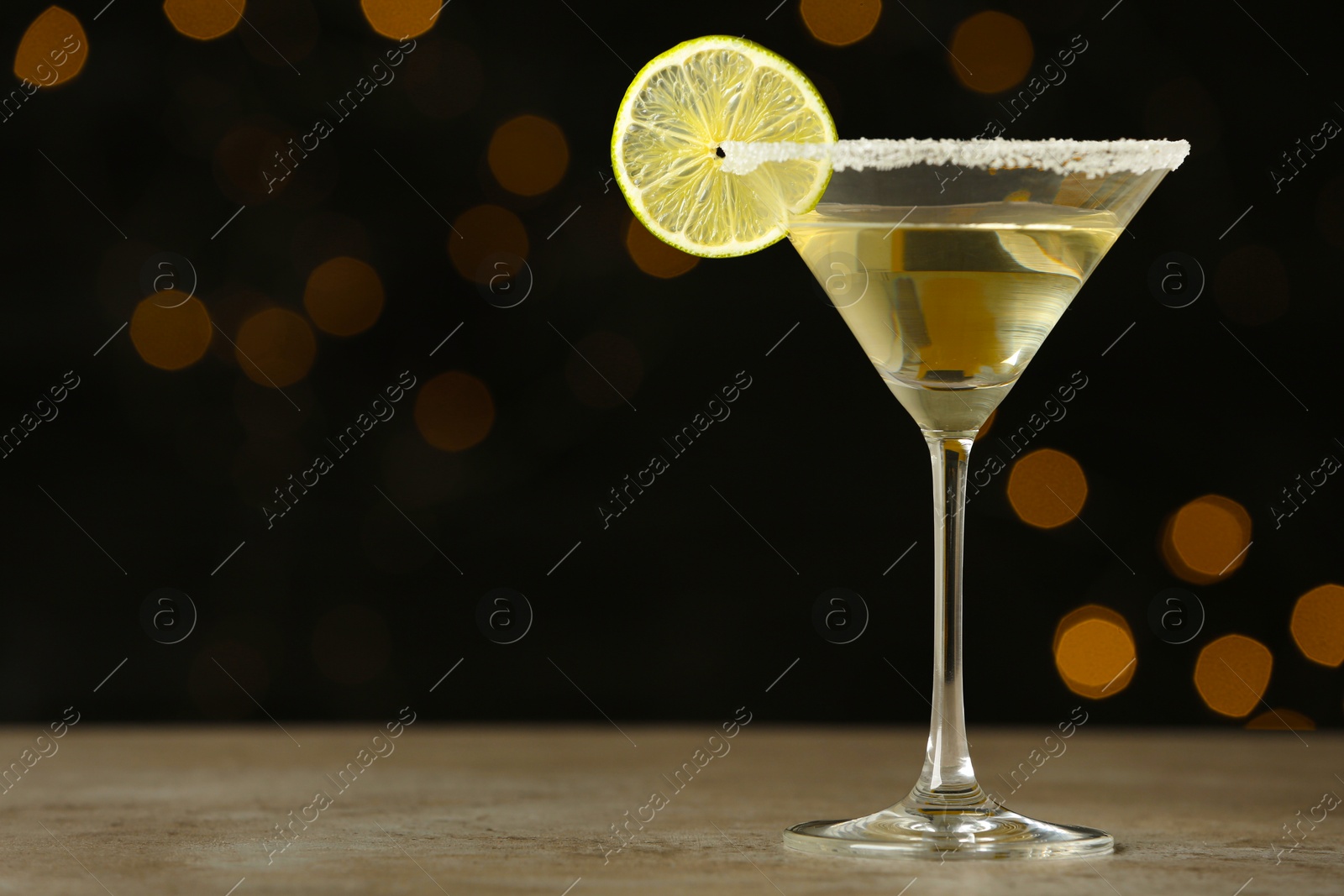 Photo of Glass of Lime Drop Martini cocktail on grey table against blurred background. Space for text