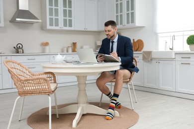 Businessman in underwear pretending to wear formal clothes during video call at home