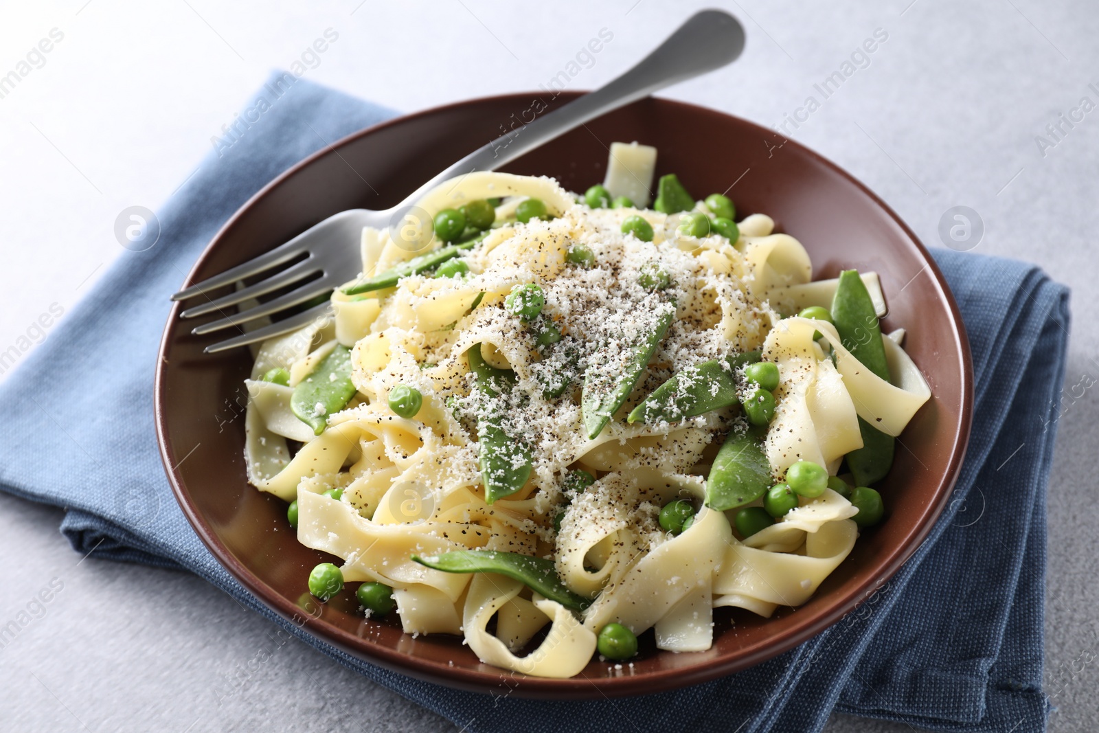 Photo of Delicious pasta with green peas and cheese served on grey table