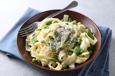 Photo of Delicious pasta with green peas and cheese served on grey table