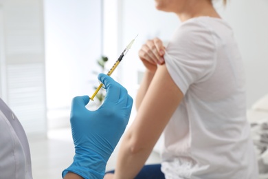 Photo of Doctor giving injection to woman in hospital, closeup. Immunization concept