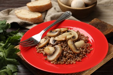 Photo of Tasty buckwheat with mushrooms and fork on table, closeup