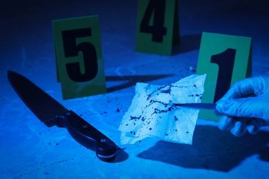 Photo of Closeup view of woman taking bloody napkin at marble background, toned in blue. Crime scene