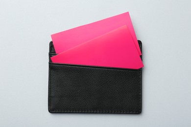 Photo of Leather business card holder with colorful cards on light grey background, top view