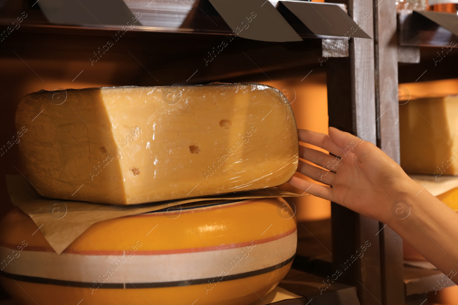 Photo of Woman choosing tasty cheese from display in store