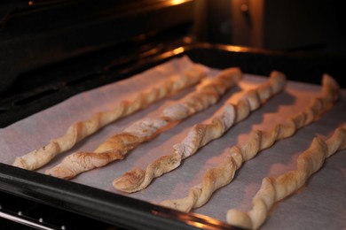 Baking tasty homemade breadsticks in oven, closeup. Cooking grissini