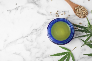 Photo of Jar of hemp cream and seeds on marble table, flat lay with space for text. Organic cosmetics