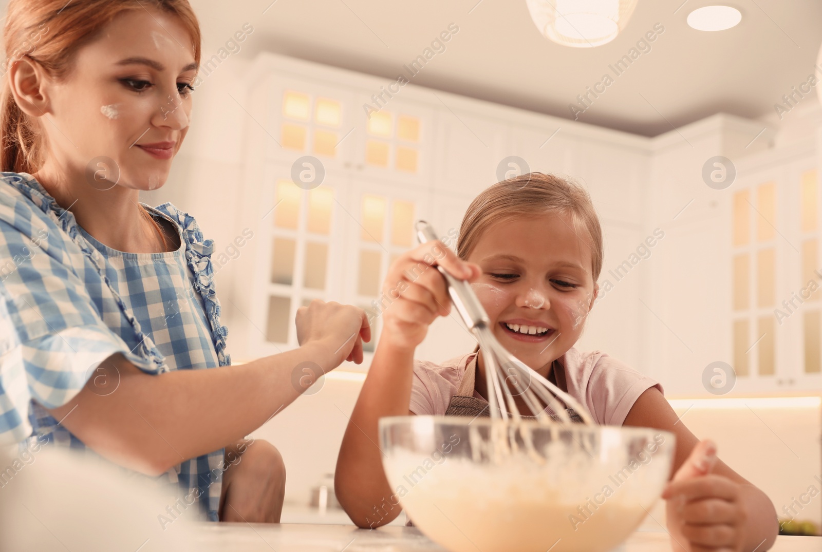 Photo of Mother and daughter making dough together in kitchen