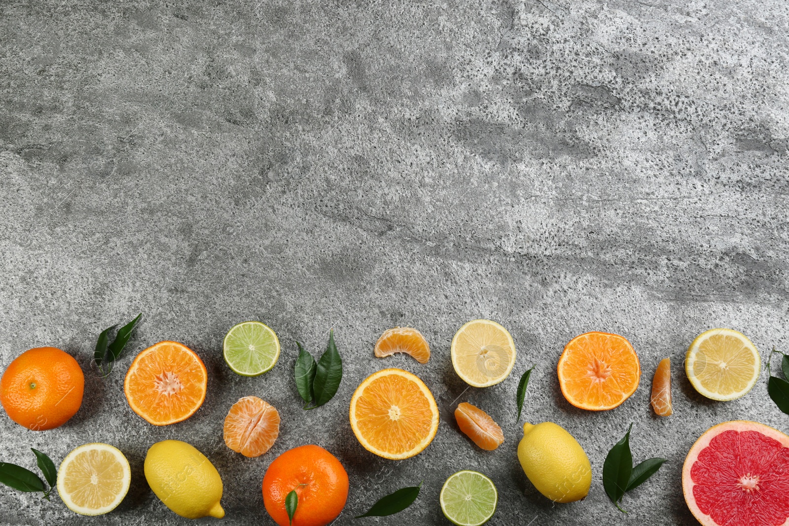 Photo of Flat lay composition with tangerines and different citrus fruits on grey background. Space for text