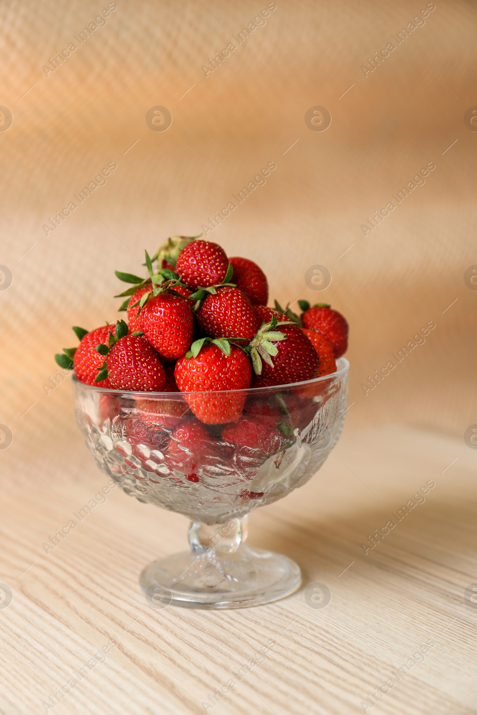 Photo of Glass dessert bowl with ripe strawberries on white wooden table