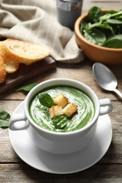 Photo of Fresh vegetable detox soup made of spinach with croutons in dish served on table