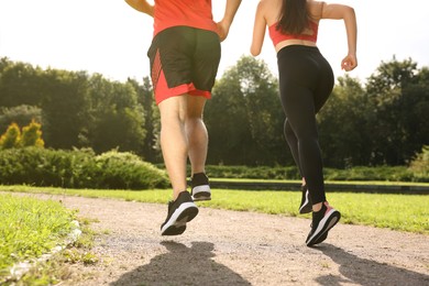 Healthy lifestyle. Couple running in park on sunny day, closeup