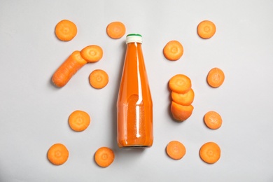 Flat lay composition with drink in bottle and cut carrot on color background