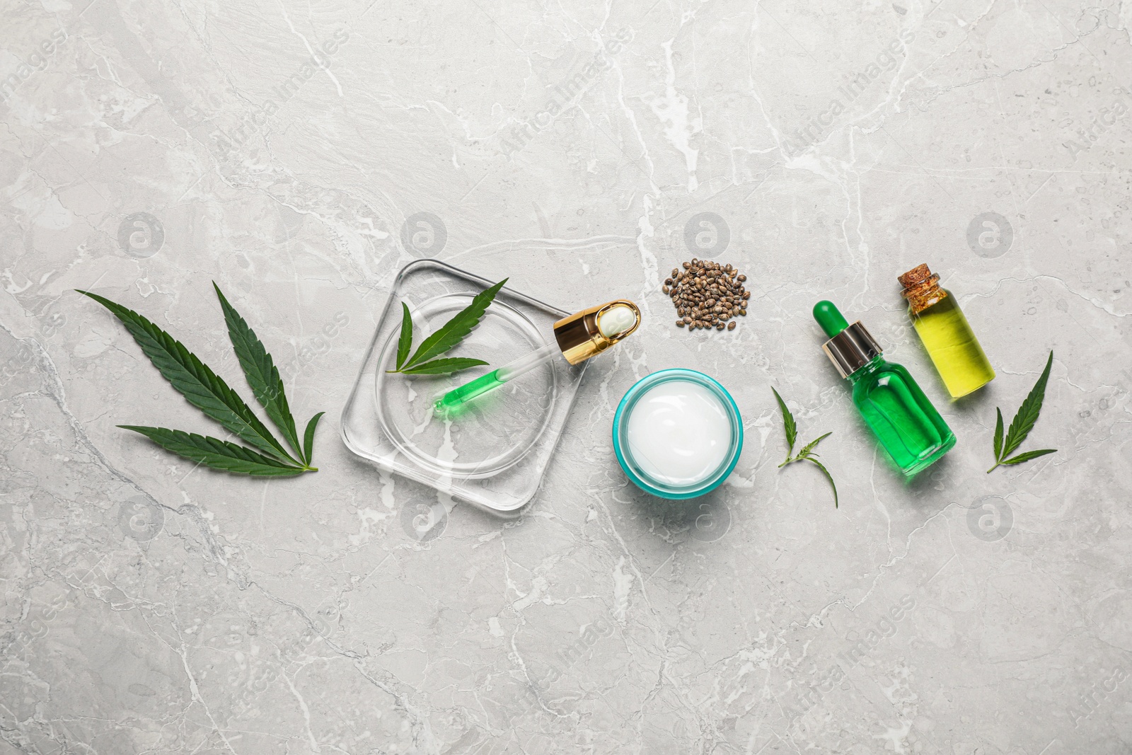 Photo of Hemp cosmetics and green leaves on light table, flat lay