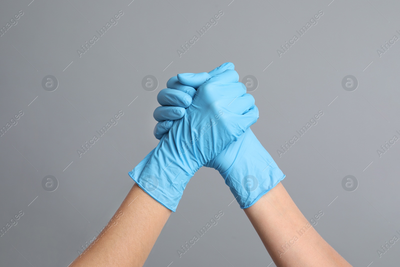 Photo of Doctors in medical gloves shaking hands on grey background, closeup