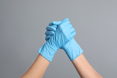 Photo of Doctors in medical gloves shaking hands on grey background, closeup