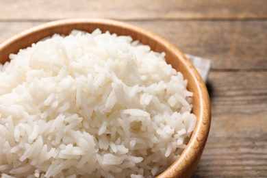 Bowl of delicious rice on wooden table, closeup