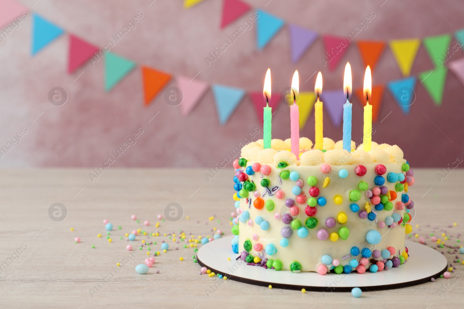 Photo of Cute bento cake with tasty cream and burning candles on white wooden table. Space for text