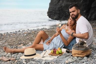 Photo of Young couple having picnic on beach near sea. Space for text