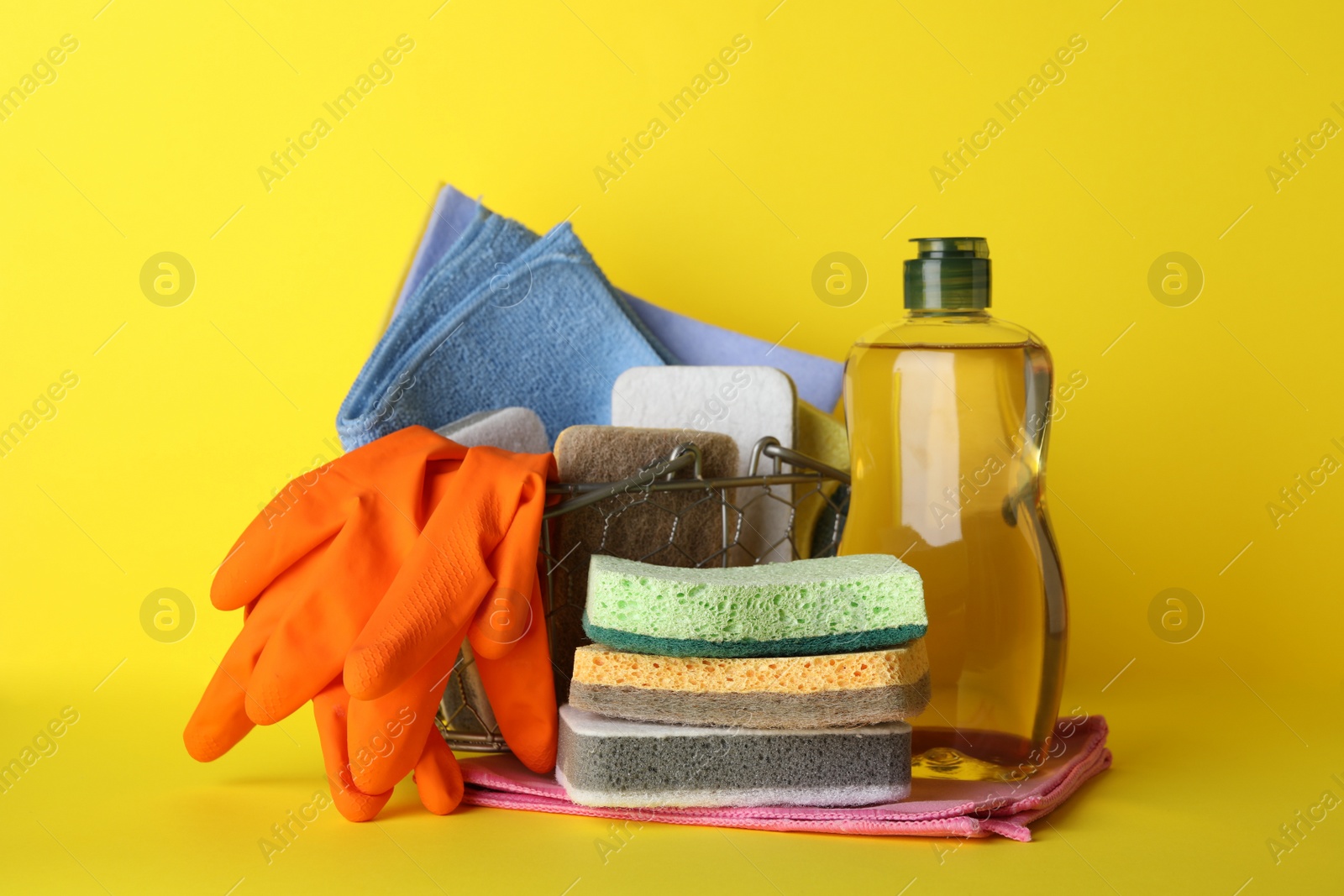 Photo of Sponges and other cleaning products on yellow background