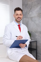 Photo of Happy doctor with clipboard and pen in clinic
