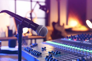 Photo of Microphone near professional mixing console in radio studio, closeup