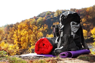 Photo of Set of camping equipment with sleeping bag on ground outdoors. Space for text