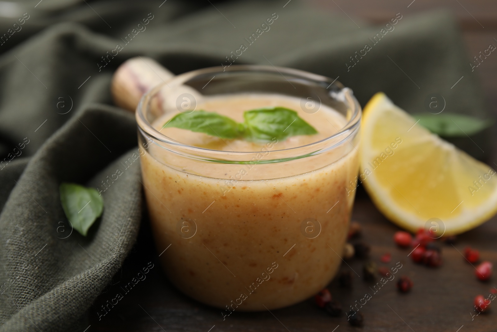 Photo of Delicious turkey gravy, basil, peppercorns and lemon on table, closeup