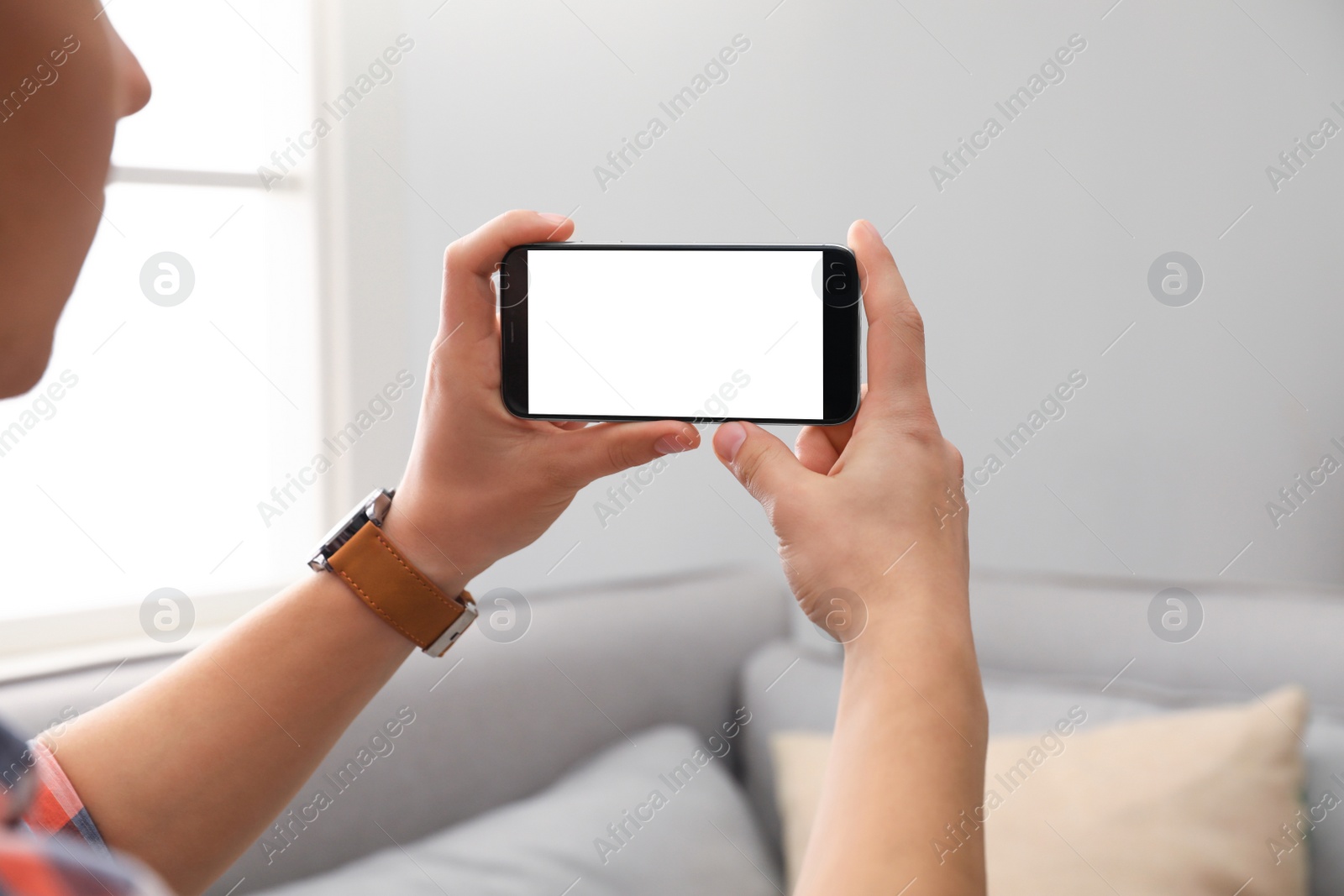 Photo of Man holding smartphone with blank screen indoors, closeup of hands. Space for text