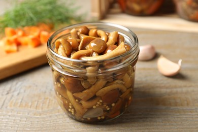 Photo of Delicious marinated mushrooms in glass jar on wooden table