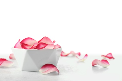 Photo of Bowl with rose petals on table against white background. Space for text